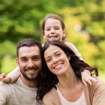 happy family in summer park family, parenthood, adoption and people concept - happy mother, father and little girl in summer park